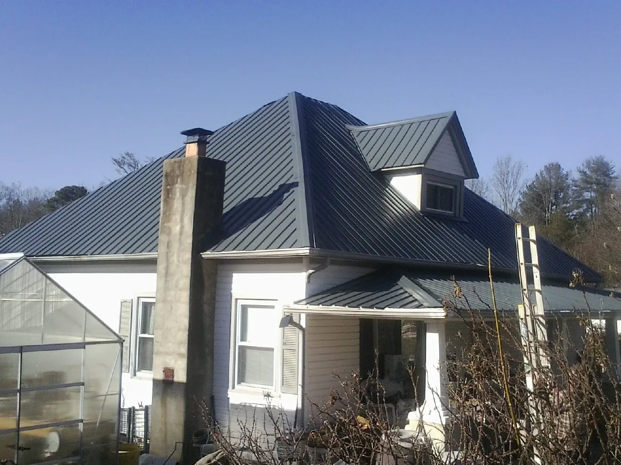 Dark blue standing seam metal roof on a white farmhouse with dormer — Slate & Tile Roof Repair by Roofing Brothers in Chelan Falls