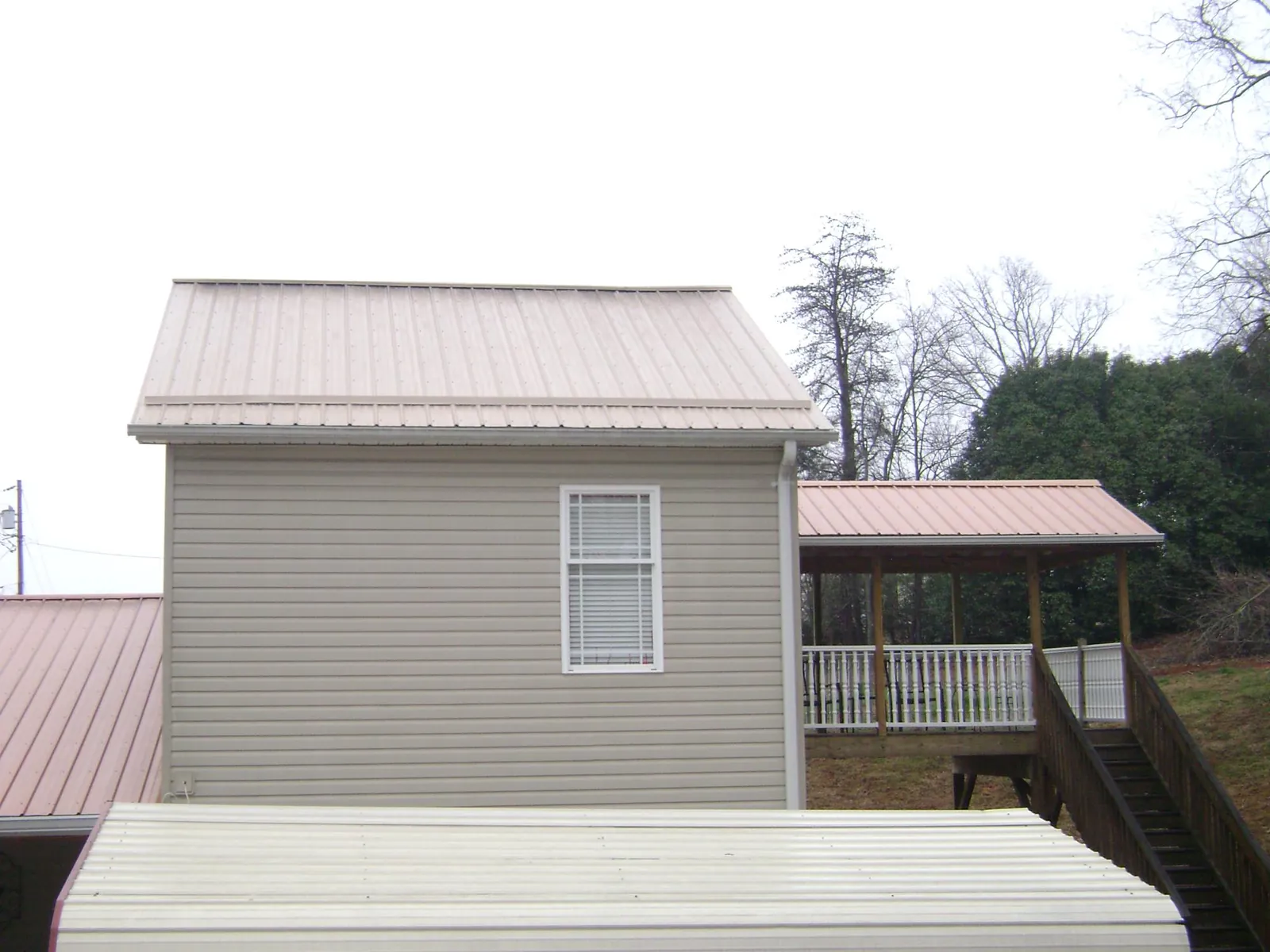Tan metal roofs on a two story addition and attached porch, from a Roof Replacement job in Chelan Falls