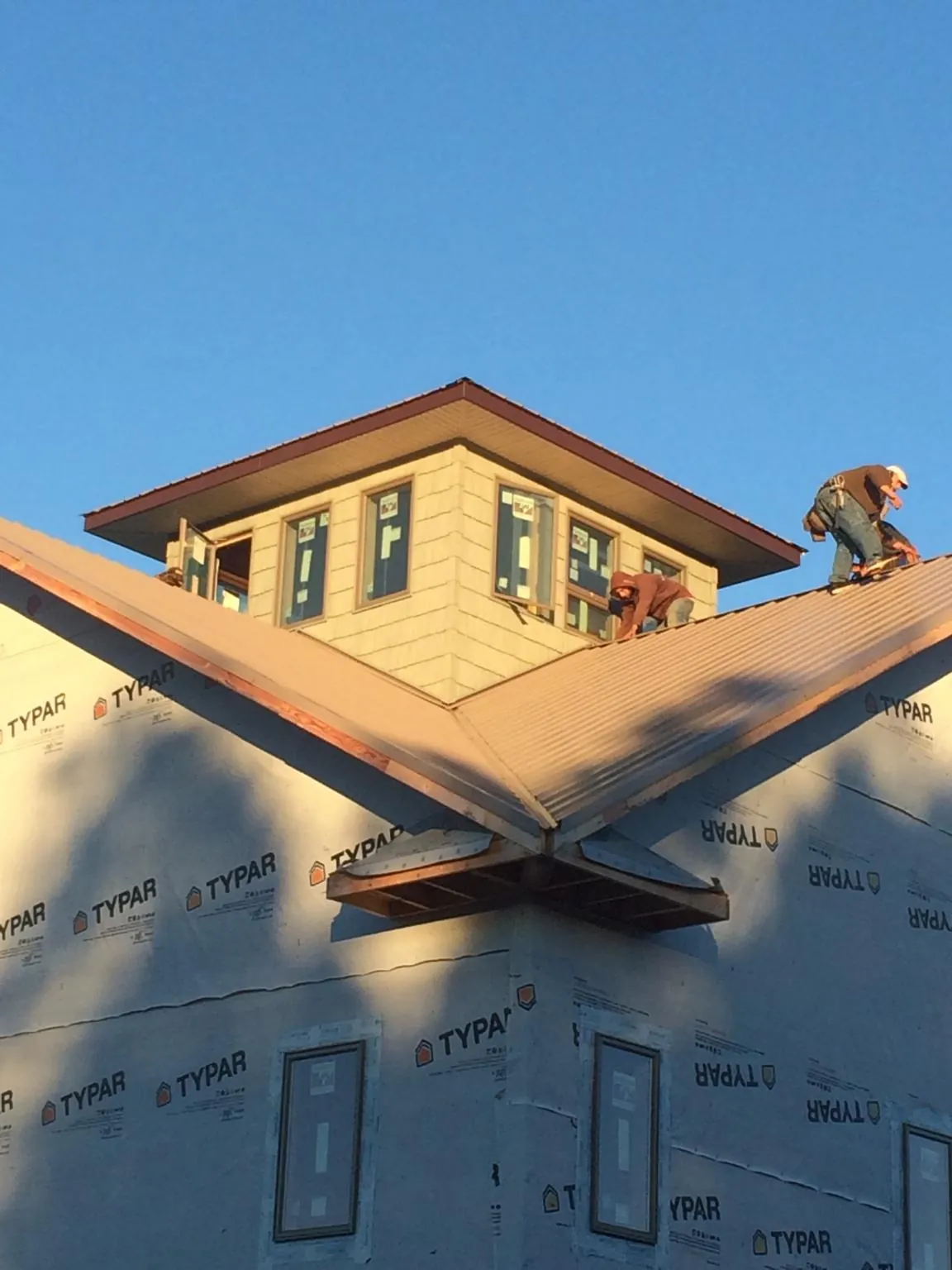 Roofers working around a rooftop cupola on a new metal roof at sunset — Roof Waterproofing in Chelan Falls by Roofing Brothers